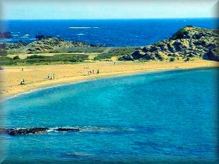 La playa de Cala Mesquida es amplia y de buenas condiciones para el baño mirando a las casas de la Mesquida al pie del bulker de defensa 