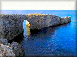 vista del area virgen de Pont d`en Gil (puente de Gil) arco de piedra creado por la erocion del mar en las rocas de la costa mas al oeste de Menorca