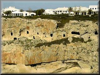 Vista de las cuevas de entrerramiento de los promitivos menorquines necropolis de Cala Canutels y los chales de la urbanizacion Ses Tanques justo por arriba